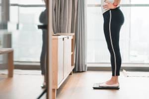 Healthy Woman Standing On A Scale To Measure Her Weight